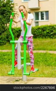 Woman making exercises on public equipment in city park. Girl working out in outdoor gym. Healthy lifestyle.. Girl training on public equipment