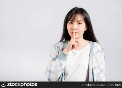 Woman making finger on lips mouth silent quiet gesture, Happy Asian beautiful young female marking silencefor stop quiet, mute studio shot isolated on white background with copy space