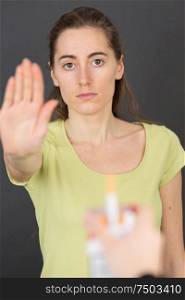 woman making hand gesture to refuse proffered cigarette