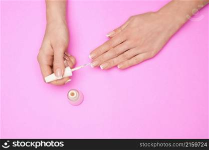 Woman making manicure by herself on pink background.. Woman making manicure by herself on pink background