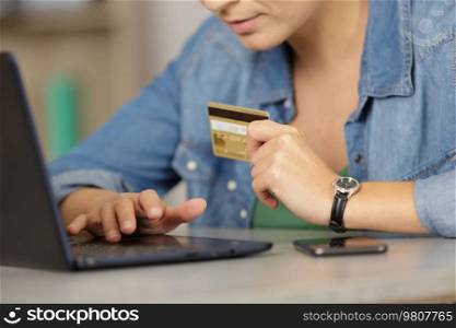 woman making online purchase on laptop and paying by card