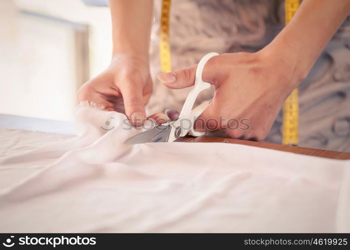 Woman making patterns. Close up of sewer hands cutting cloth with scissors