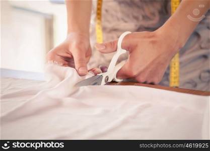 Woman making patterns. Close up of sewer hands cutting cloth with scissors