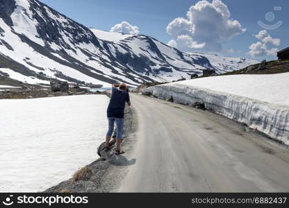 woman making photo of the snow on the gamle strynefjellsvegen road, one of the most beautifull auto roads in norway with snow in summer