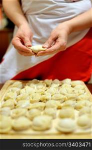 Woman making russian dumplings (pelmeni), focus on hands