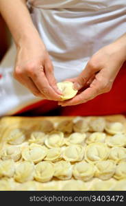 Woman making russian dumplings (pelmeni), focus on hands