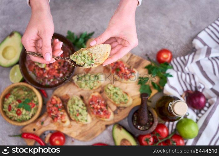 Woman making tasty salsa and guacamole bruschetta snacks at domestic kitchen.. Woman making tasty salsa and guacamole bruschetta snacks at domestic kitchen