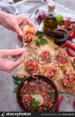 Woman making tasty salsa bruschetta snacks at domestic kitchen.. Woman making tasty salsa bruschetta snacks at domestic kitchen