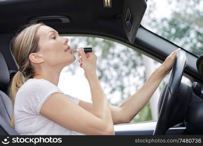 woman making up her lips in car