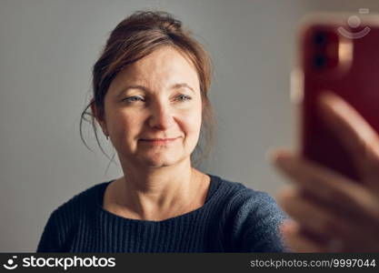 Woman making video call using mobile phone. Talking with relatives. Having fun taking selfie photo using smartphone. Keeping distance. Connecting remotely with family