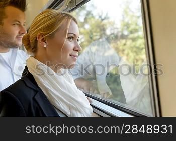Woman man looking out the train window smiling thinking friends