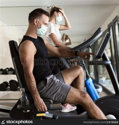 woman man working out gym with medical masks