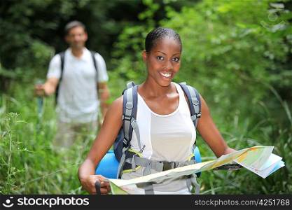 Woman map reading while hiking through long grass