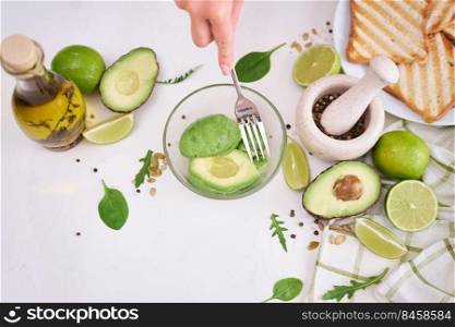 Woman mashing avocados in a glass bowl with a fork to prepare toasts.. Woman mashing avocados in a glass bowl with a fork to prepare toasts