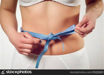 woman measuring waist with tape on knot like a gift on white background. woman measuring waist with tape on knot like a gift on white