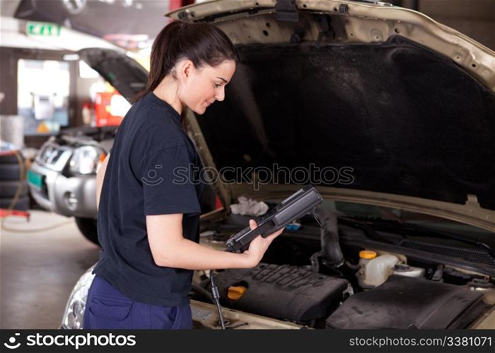 Woman mechanic looking at electronic diagnostics tool