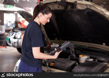 Woman mechanic looking at electronic diagnostics tool
