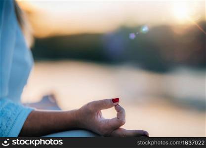 Woman meditating by the lake, sitting in lotus position. Sunset Meditation
