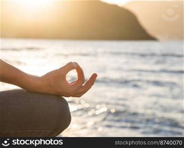 woman meditating by the sea at sunset