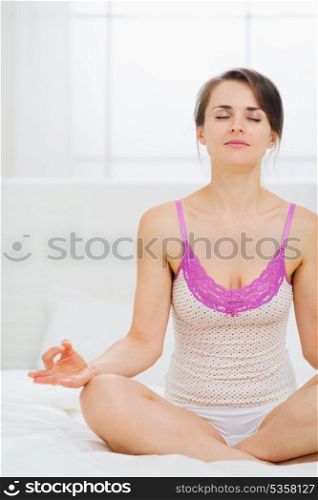 Woman meditating in bedroom