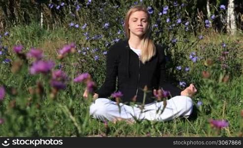 Woman meditating in the city park at summer morning