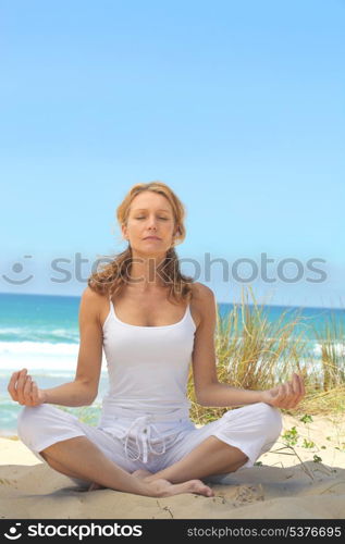 Woman meditating on a beach