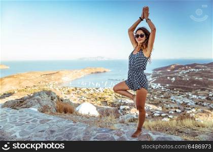 Woman meditating outdoors, beautiful female standing in yoga asana on the mountain near seaside, peaceful vacation on the beach, zen and soul balance concept. Woman doing yoga outdoors