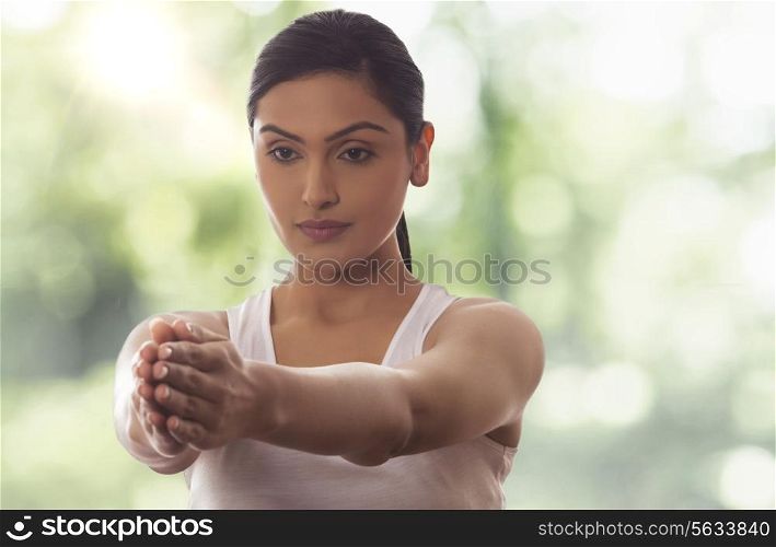 Woman meditating with arms out against glass window