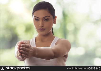 Woman meditating with arms out against glass window