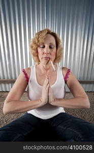 Woman meditating with cigarette in front of corrugated metal