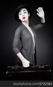 woman mime in hat with suitcase on black background
