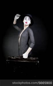 woman mime in hat with suitcase on black background&#xA;