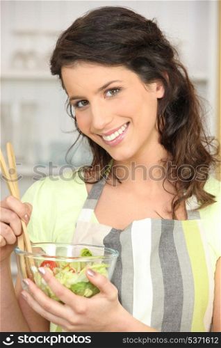 Woman mixing bowl of salad leaves