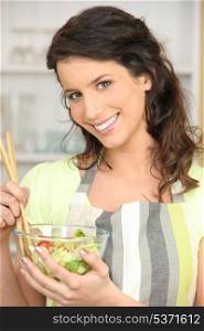 Woman mixing bowl of salad leaves
