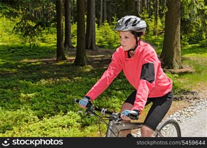 Woman mountain biking in forest on sunny day cycling path