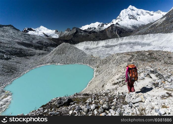 woman mountain climber hiking to a turquoise lake from base camp in the Cordillera Blanca in Peru