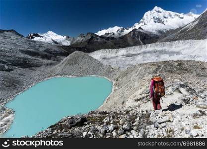 woman mountain climber hiking to a turquoise lake from base camp in the Cordillera Blanca in Peru