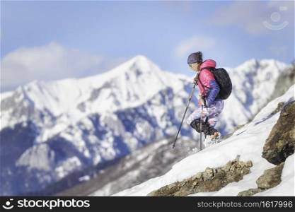 Woman mountaineer downhill with cr&ons on snowy slope