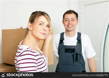 Woman moving in her new house, she is getting friendly help by a mover who is carrying the boxes
