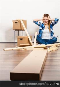 Woman moving into apartment assembly furniture.. Worried confused woman moving into new apartment house assembling furniture. Young girl arranging interior and unpacking boxes. Female holding her head.