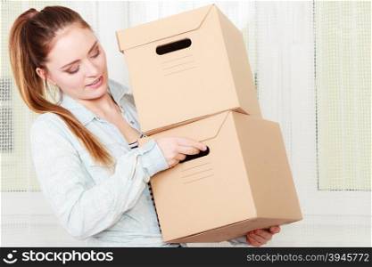 Woman moving into apartment house carrying boxes.. Woman moving in carrying cartons boxes. Young girl unpacking at new apartment house home.