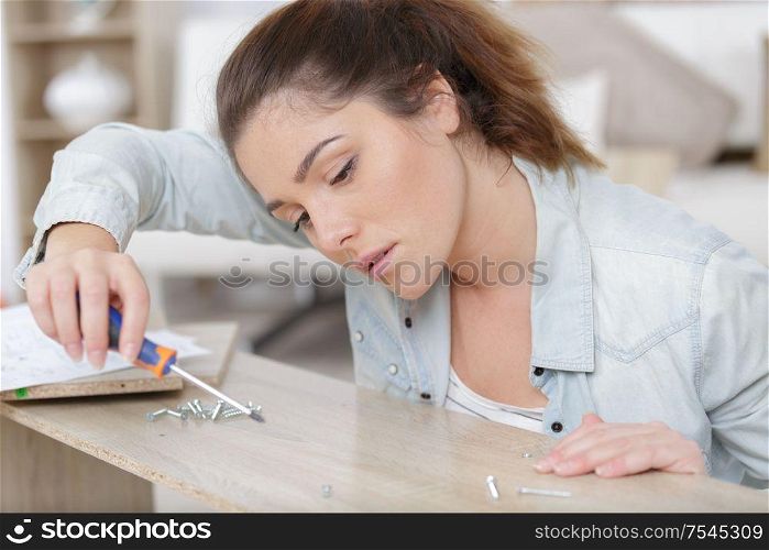 woman moving into new apartment house assembling a furniture