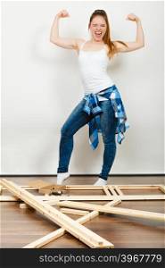 Woman moving into new apartment. Success.. Successful and strong woman moving into new apartment house with furniture to assembly. Young girl showing off muscles. Success and achievement.
