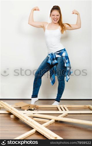 Woman moving into new apartment. Success.. Successful and strong woman moving into new apartment house with furniture to assembly. Young girl showing off muscles. Success and achievement.