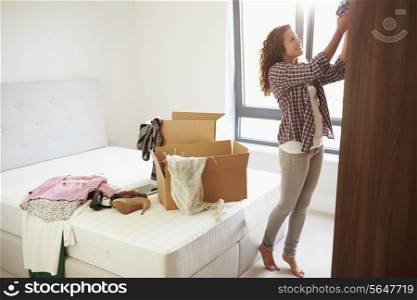 Woman Moving Into New Home And Unpacking Boxes In Bedroom