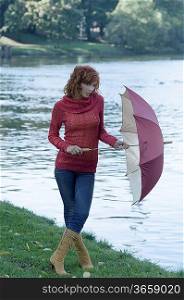 woman near a river with umbrella after a fall rain