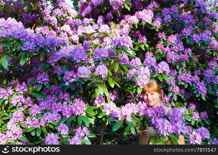 Woman near blossoming bush with pink flowers . Summer landscape.