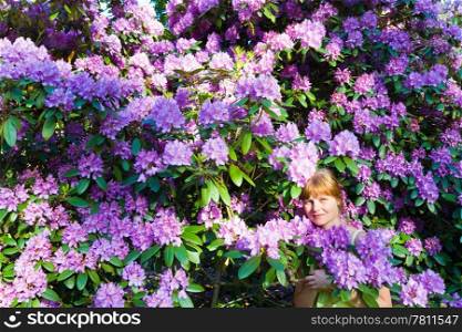 Woman near blossoming bush with pink flowers . Summer landscape.