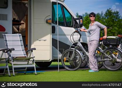Woman next to a bicycle near the camper. Caravan car Vacation. Family vacation travel, holiday trip in motorhome