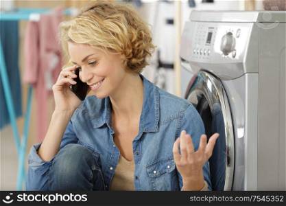woman next to washing machine talking on the cellphone